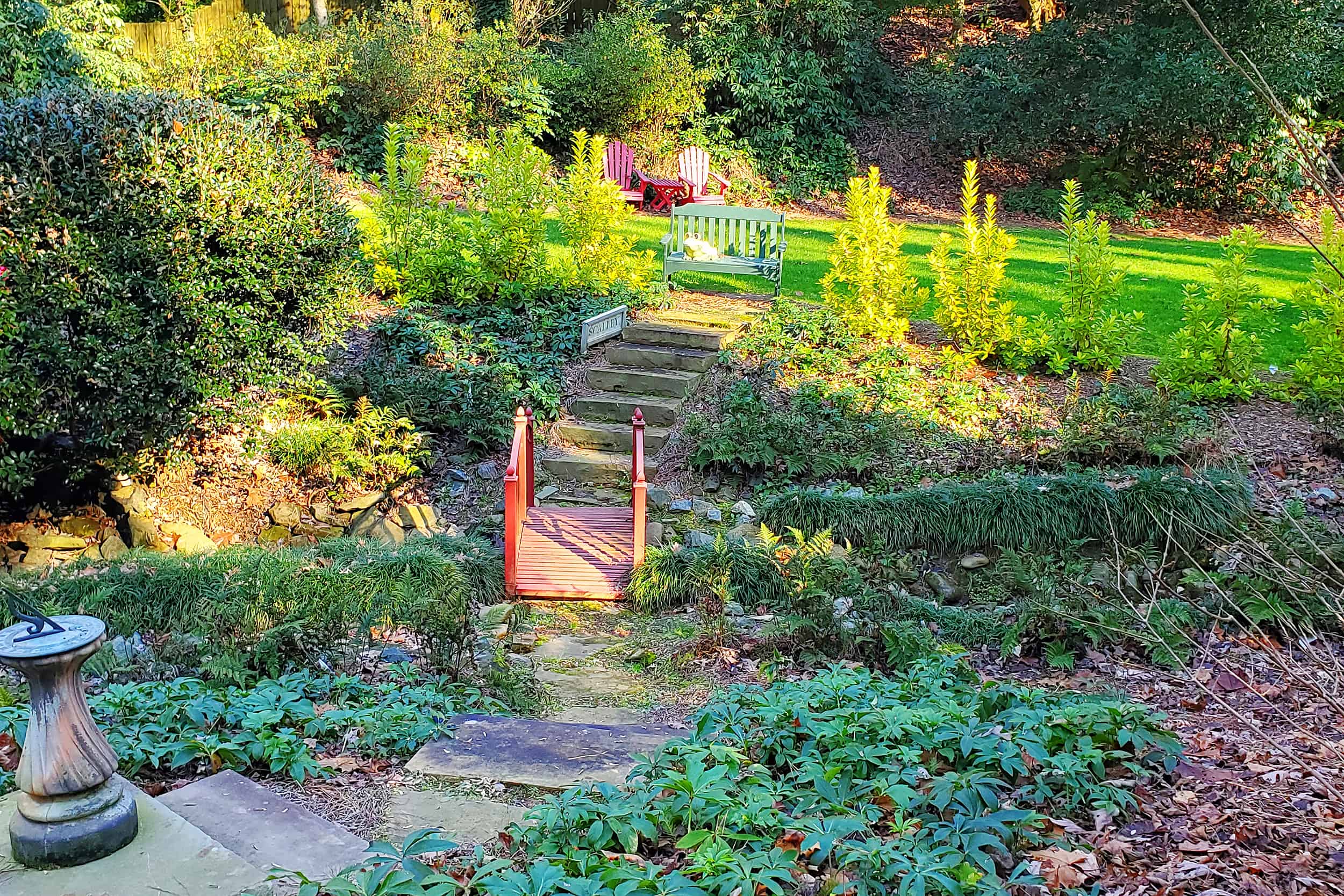 Hillside landscaping with deer resistant plants and a red bridge in Atlanta 1